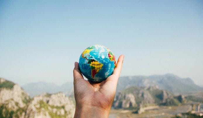 A person looking at a small globe in the mountains