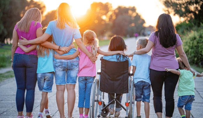 an image shows a group of people, including children and adults, standing together outdoors at sunset